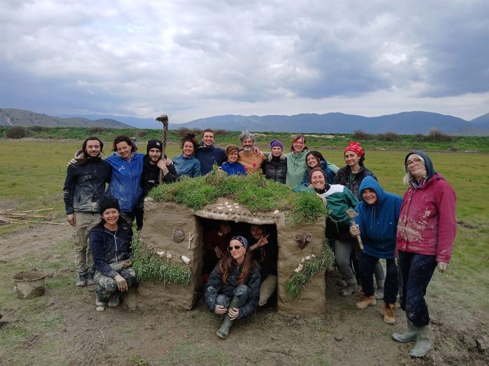 Permaculture Design Course, Nessonas (Greece), March 2026: the intergenerational group and the raw-earth shelter they built together.